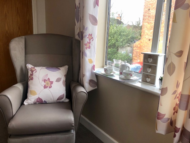 armchair next to a window with tea tray